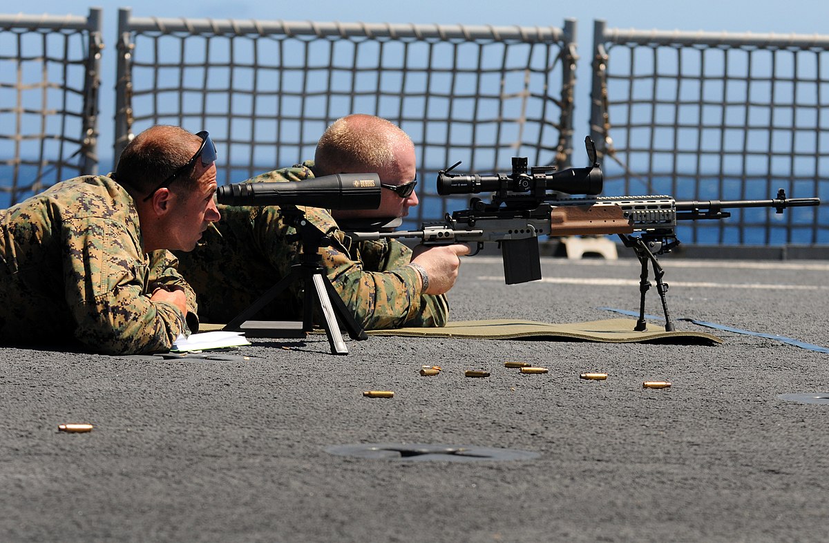 a navy aiming the target using a firearm with riflescope