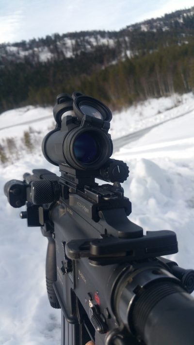close-up photo of an automatic rifle with scope being used on a snowy environment