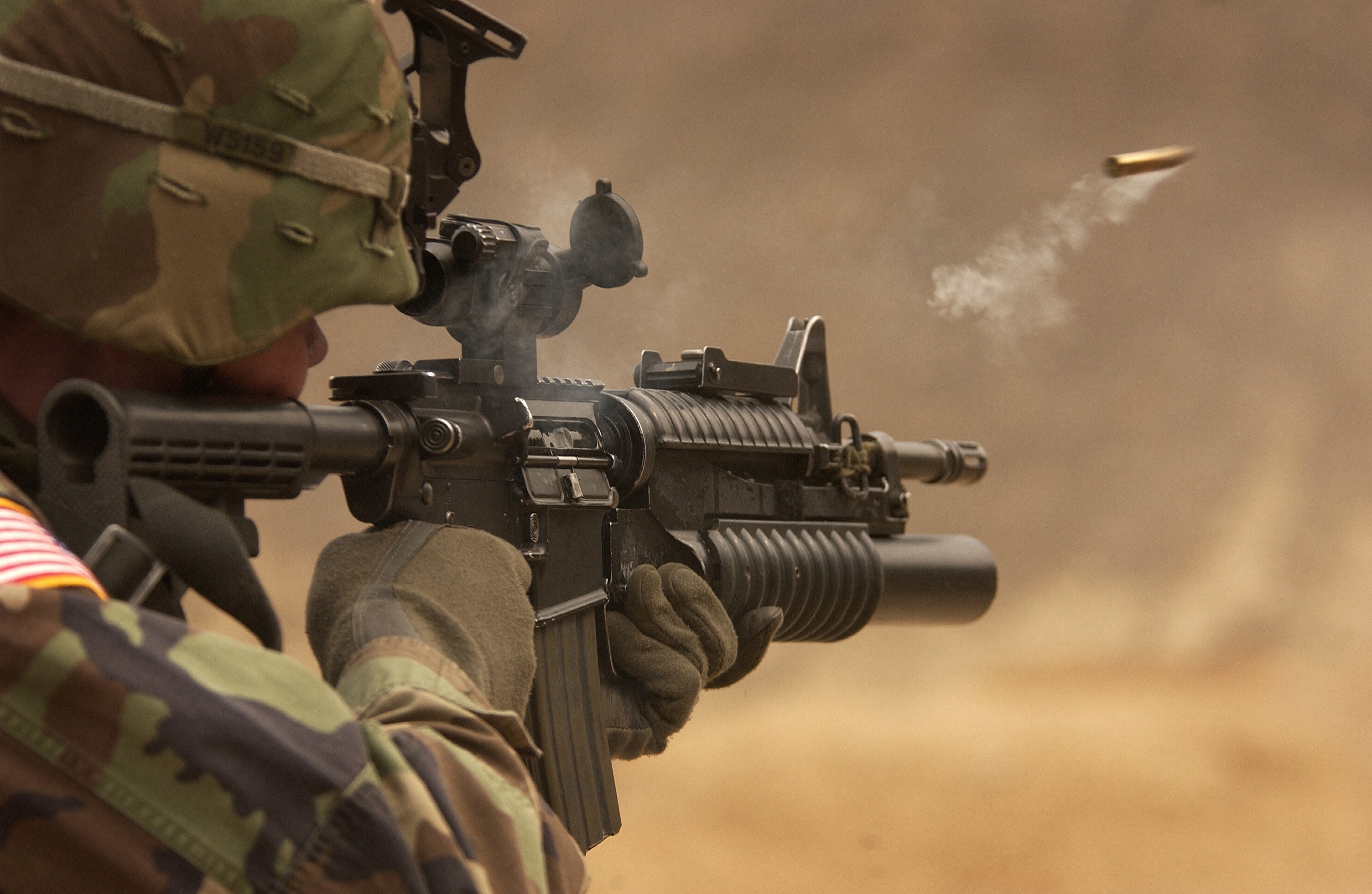 a soldier firing a firearm with attached scope