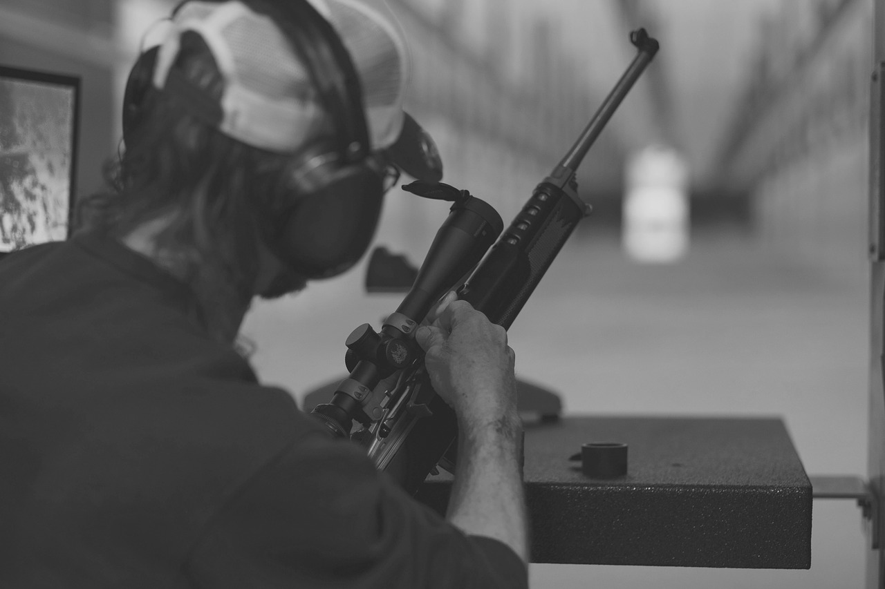black and white photo of a man preparing to use a rifle with 4x scope during a target practice shooting