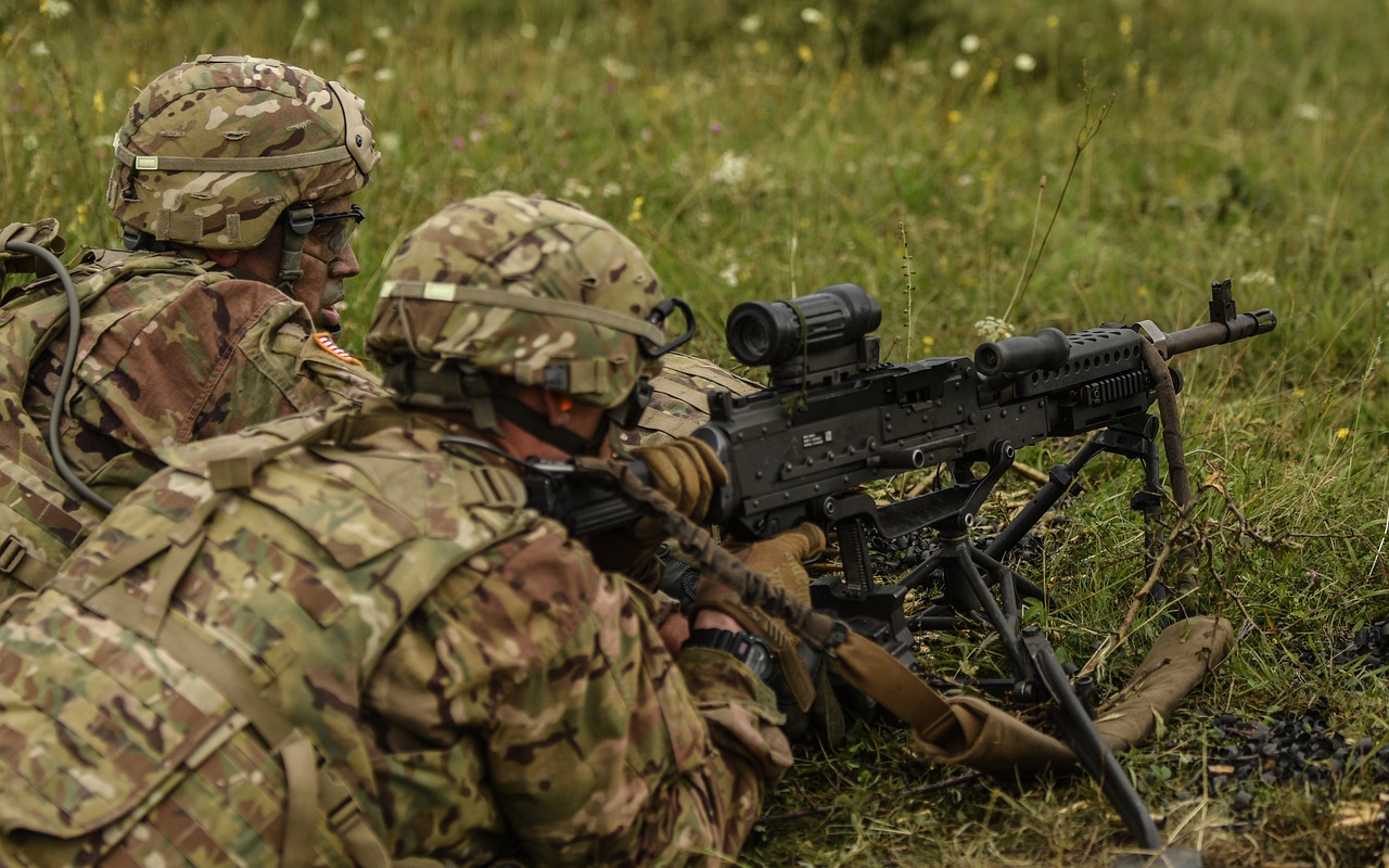 a soldier lying on the ground and looking through the scope installed on the firearm