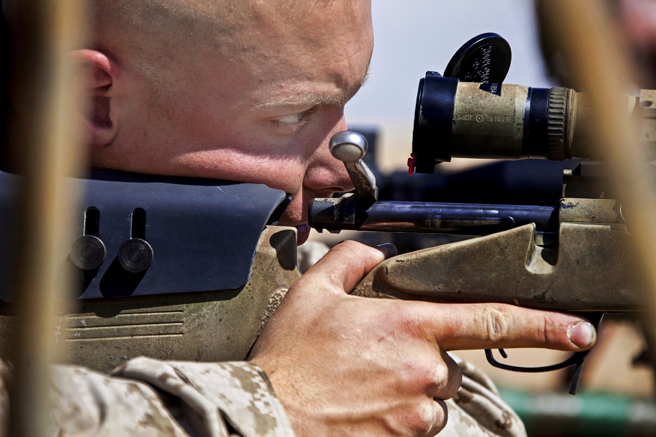 close-up photo of a soldier looking through a long-range scope attached to a rifle